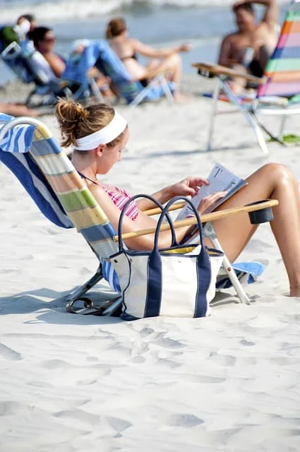 Woman relaxing on a sunny beach chair, reading a book, symbolizing a peaceful trip from Orlando to Vero Beach, Florida